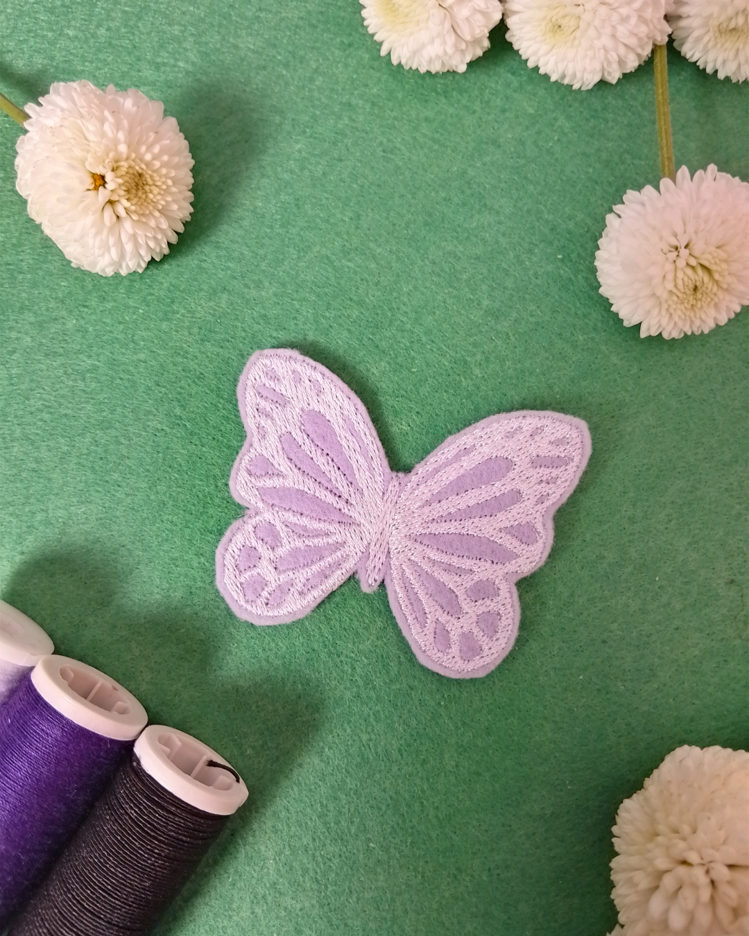 Weißer Schmetterling als gestickter Aufnäher auf lila Hintergrund